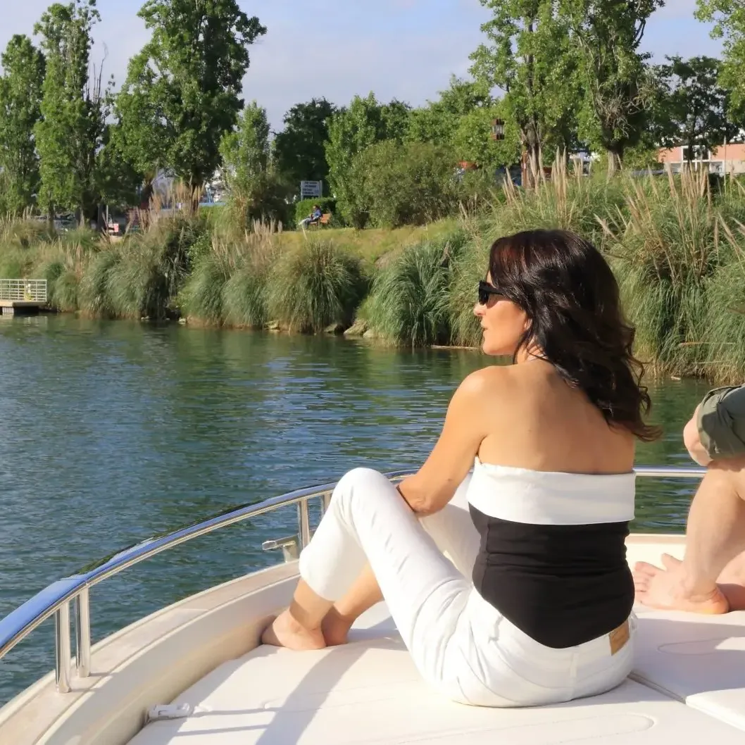 Un homme et une femme assis à l'avant d'un bateau sur un plan d'eau entouré de végétation et de bâtiments