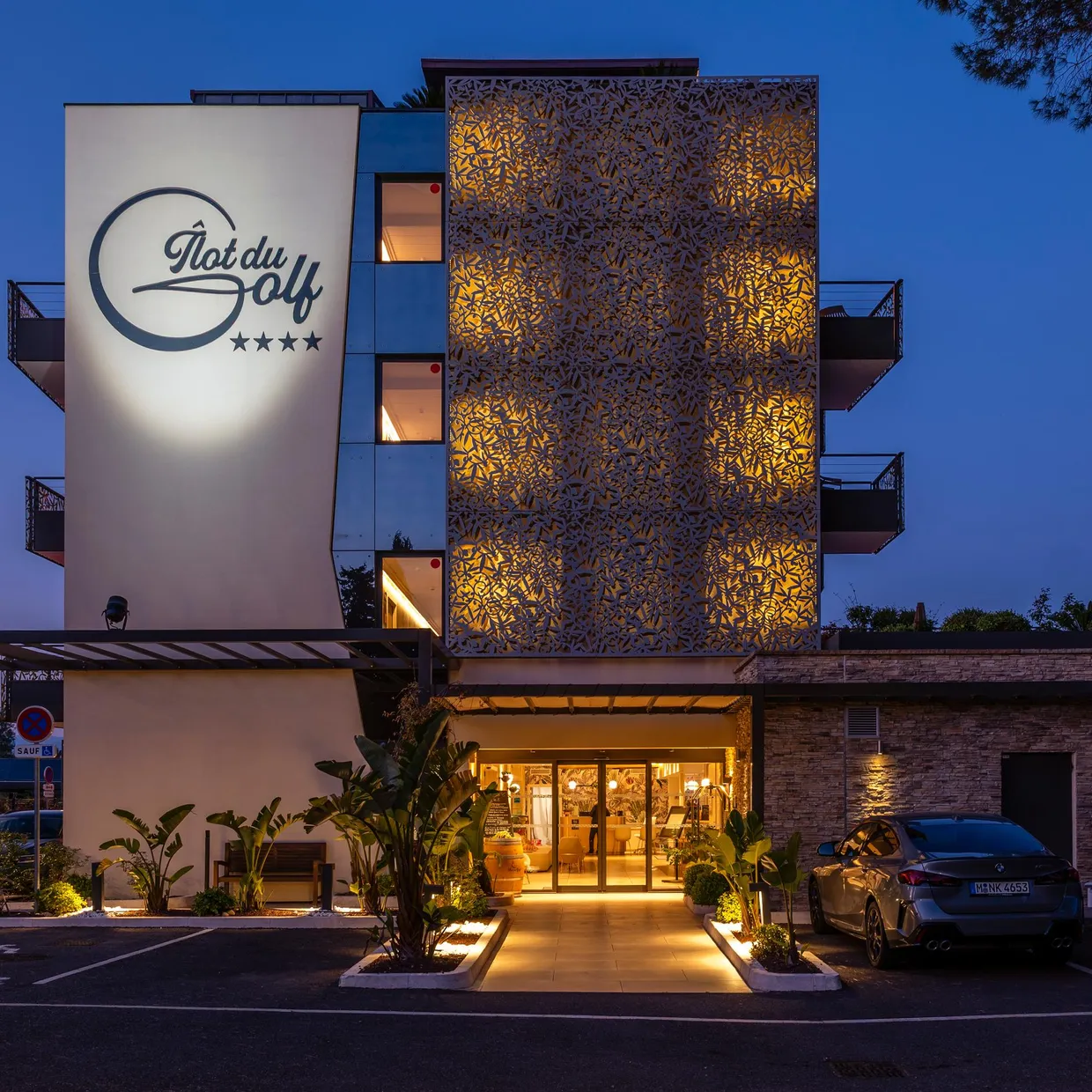 Hôtel "Plat du Golf" de quatre étoiles avec façade éclairée et entrée accessible par un chemin pavé