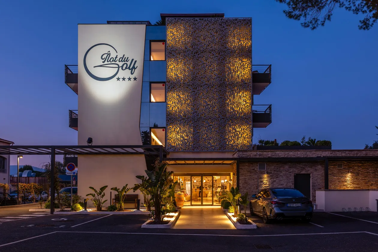 Hôtel "Plat du Golf" de quatre étoiles avec façade éclairée et entrée accessible par un chemin pavé