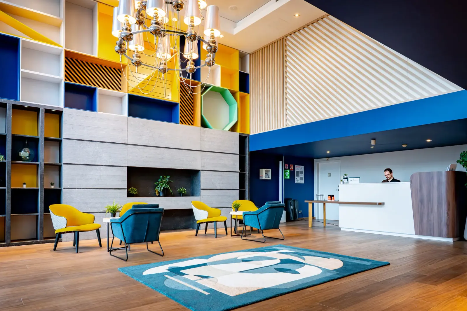 Un hall d'accueil moderne avec des chaises colorées, une réception et un éclairage suspendu