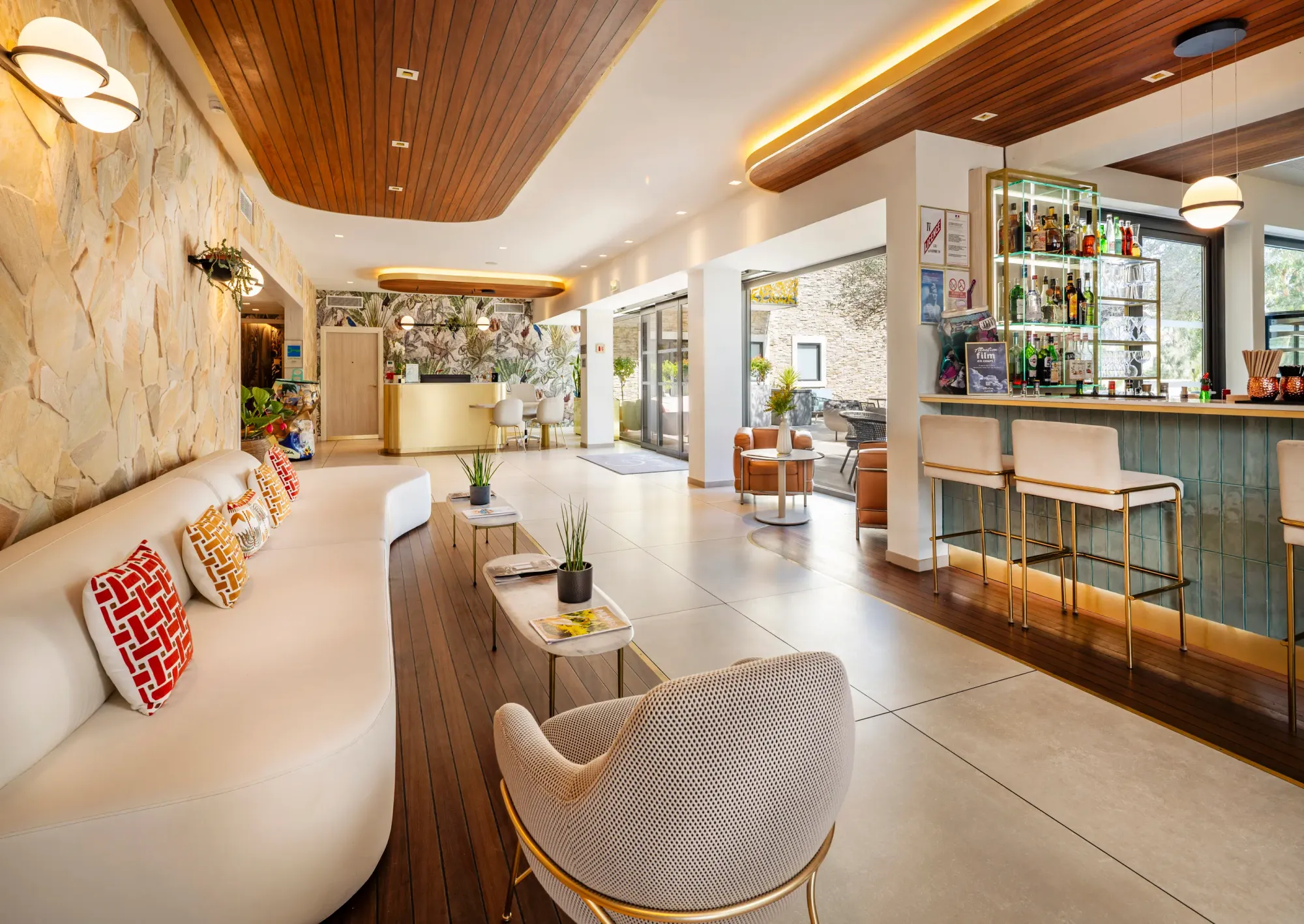 Un espace intérieur moderne avec un canapé, des chaises, des tables basses et un bar, éclairé par des lampes suspendues