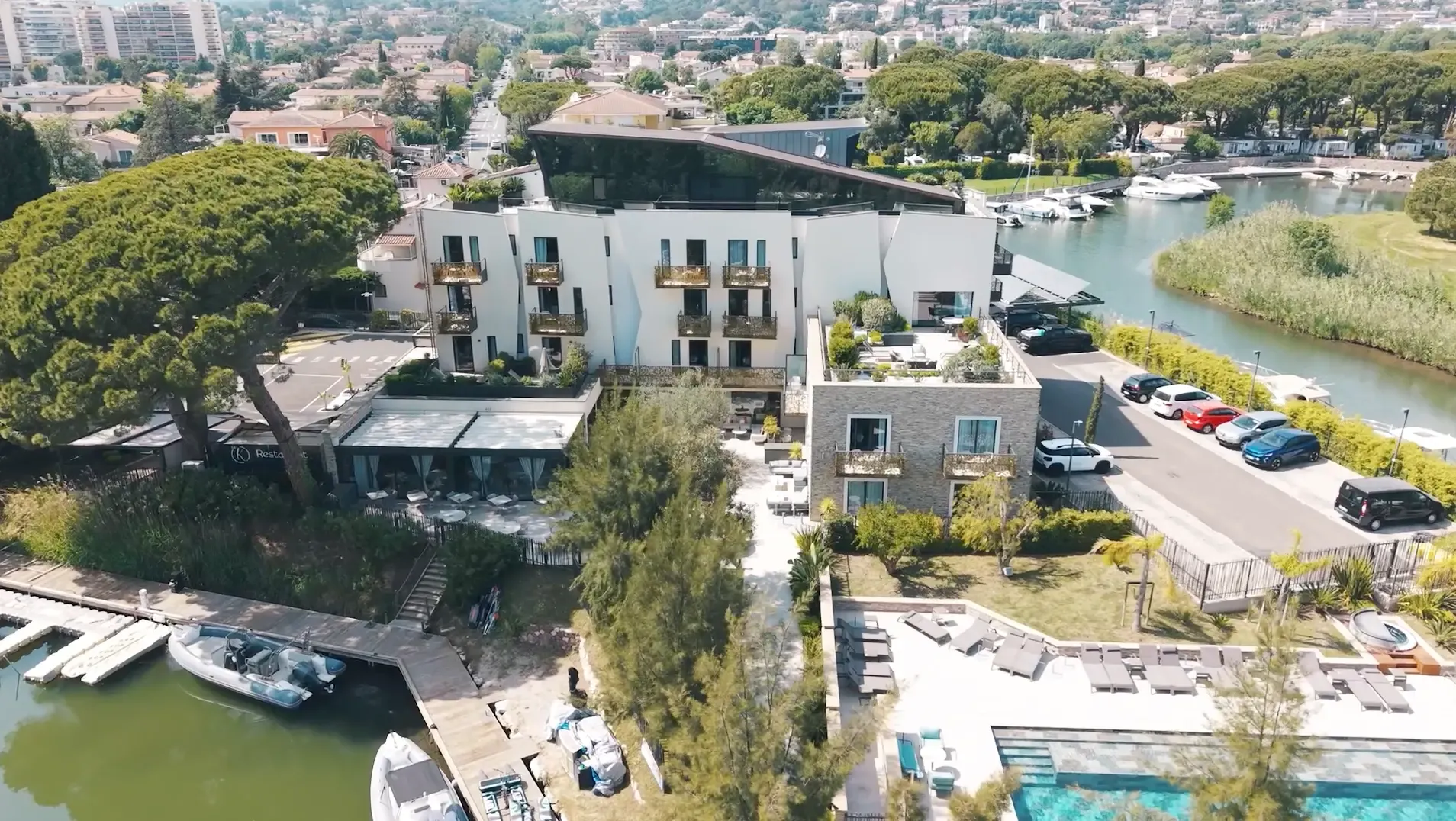 Vue aérienne d'un complexe hôtelier en bord de rivière avec piscine, restaurant et embarcadère