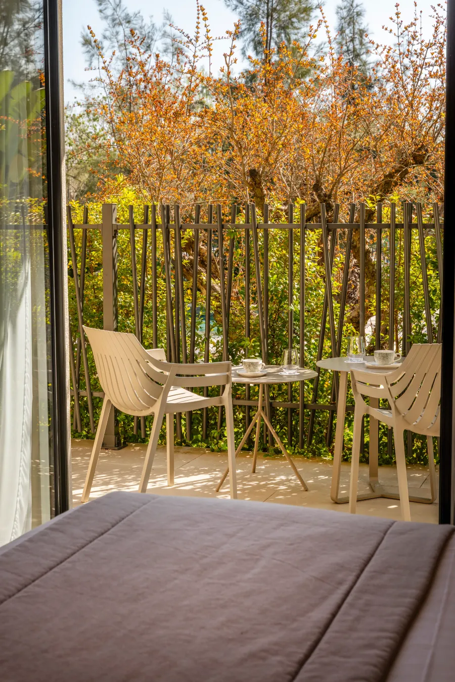 Balcon avec deux tables, chaises et une vue sur un jardin avec des plantes et des arbres
