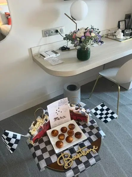 Un plateau avec des gâteaux et des pop-corns est posé sur une couverture à carreaux noirs et blancs devant un bureau avec un vase de fleurs